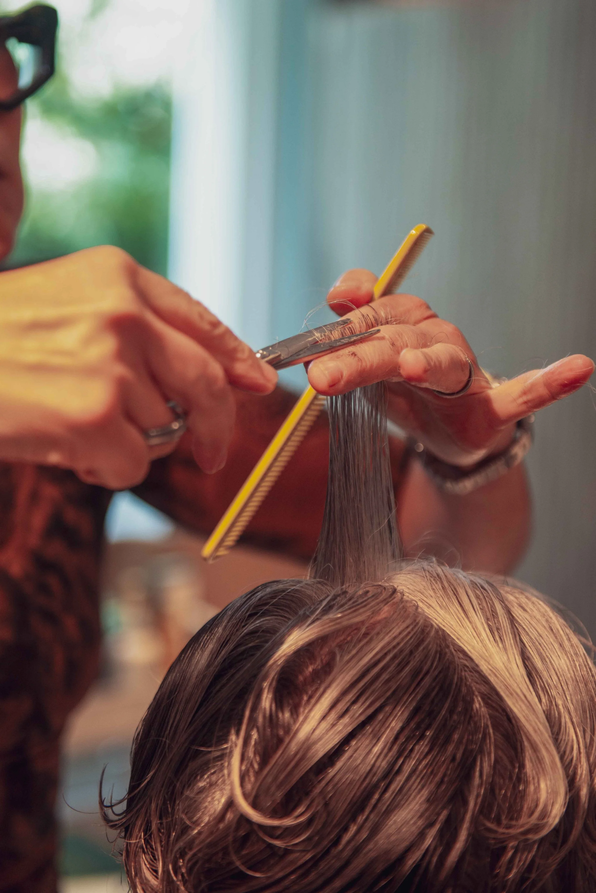 Hairdresser cutting a person's wet hair with scissors in a salon.