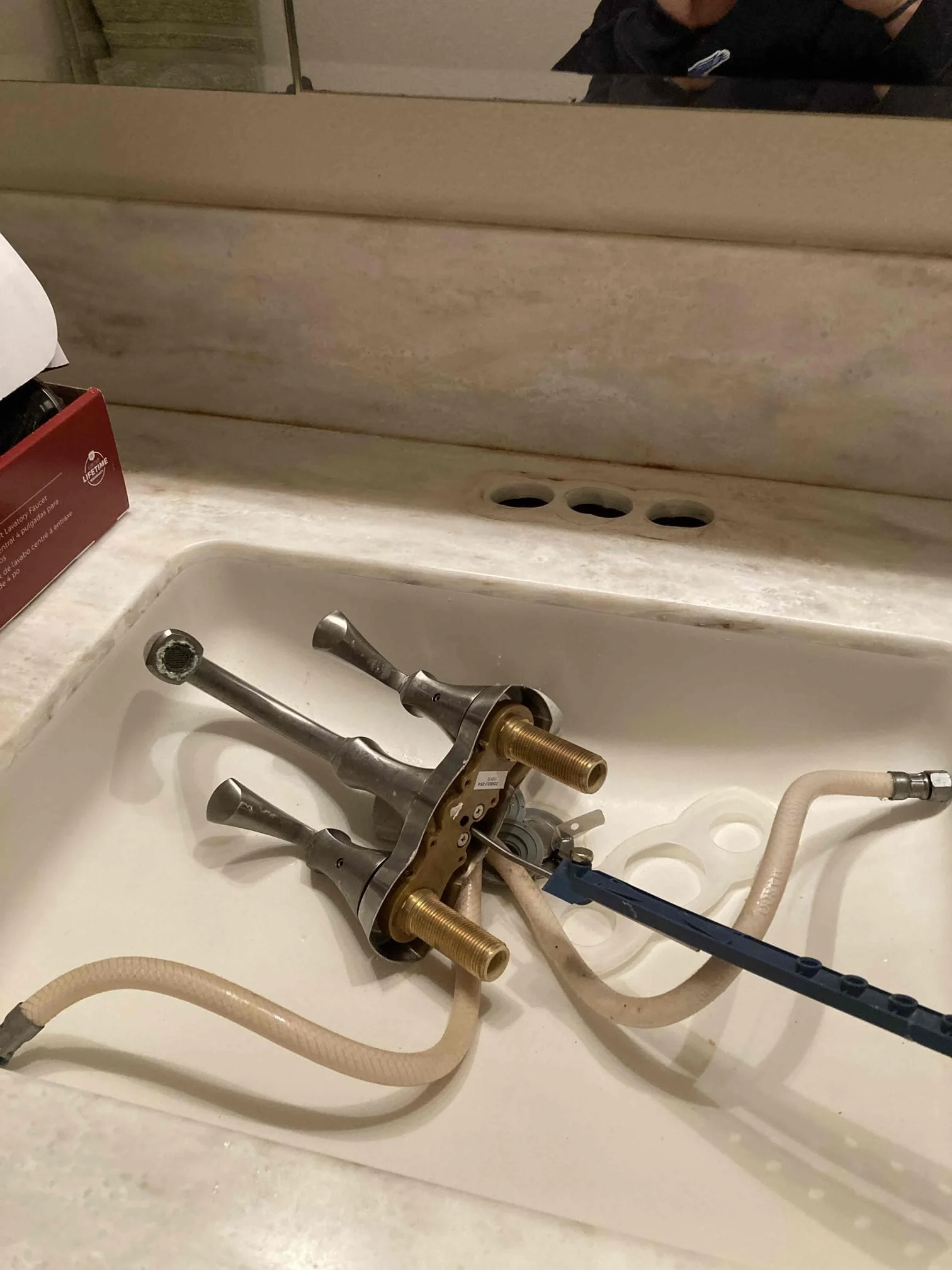 Disassembled faucet and pipe parts in a bathroom sink.
