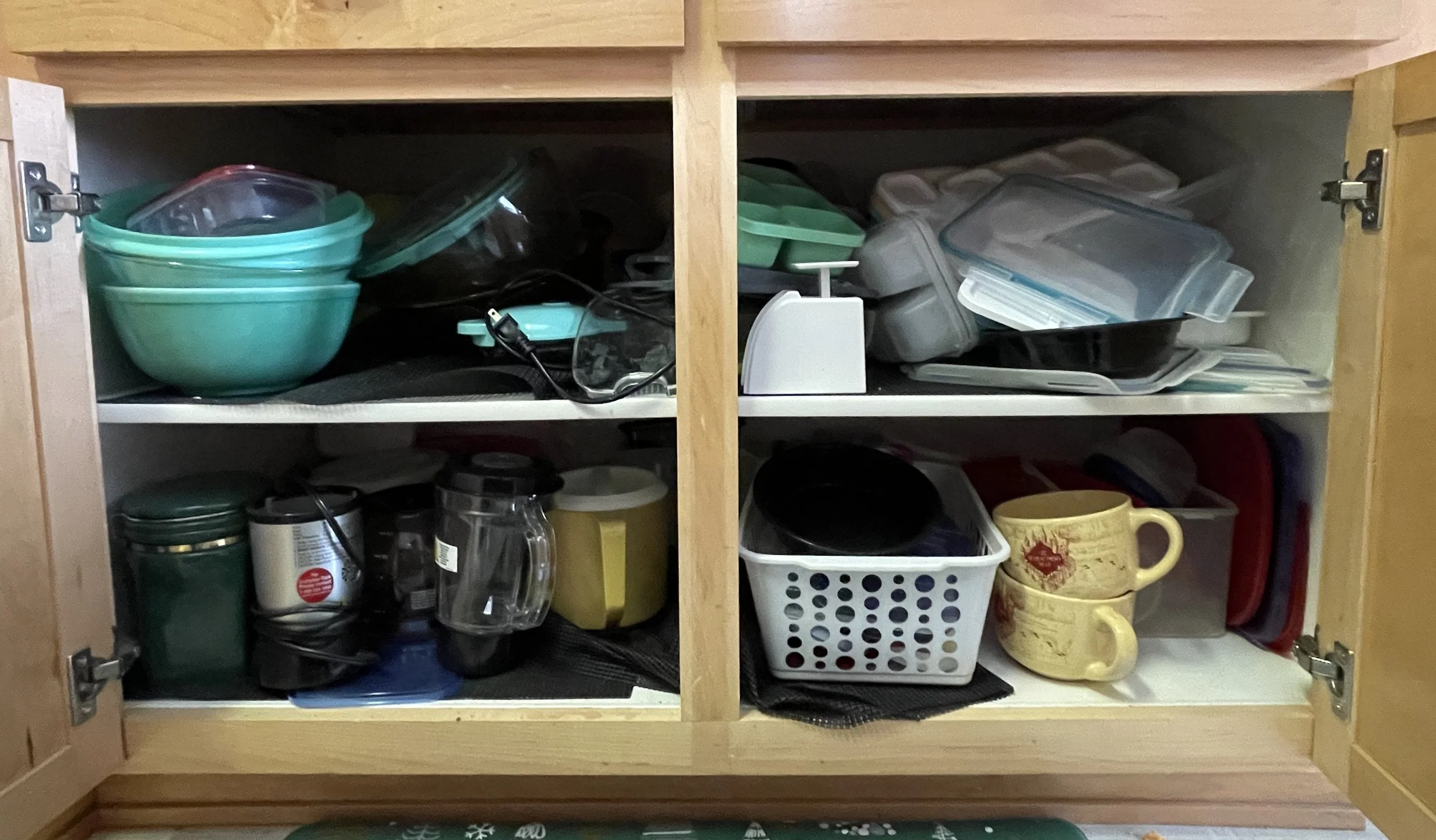 Open kitchen cabinet with various plastic containers, cups, and jars on shelves.