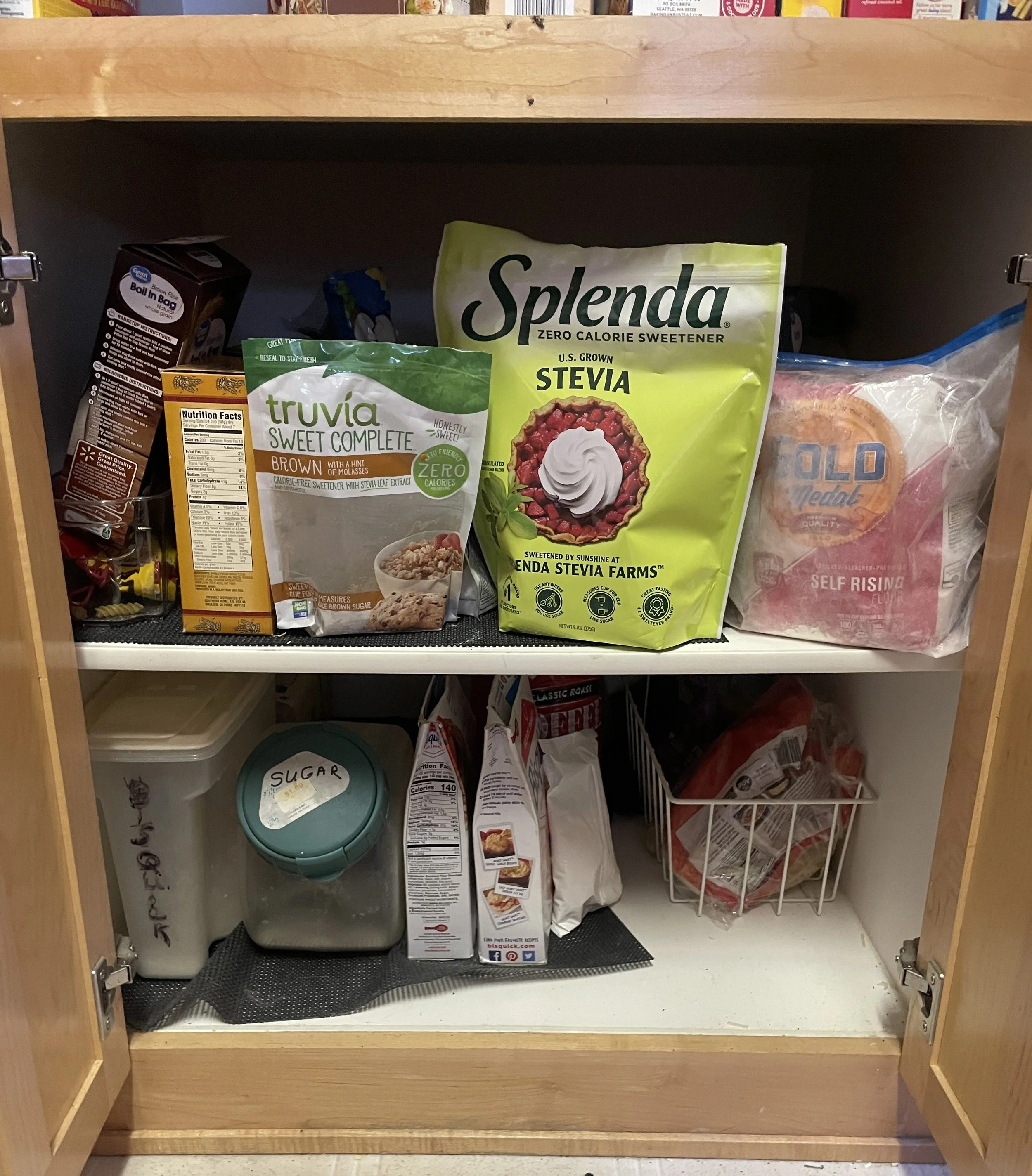 Kitchen pantry with various bags of baking supplies, including sugar, flour, and baking mixes, on shelves.
