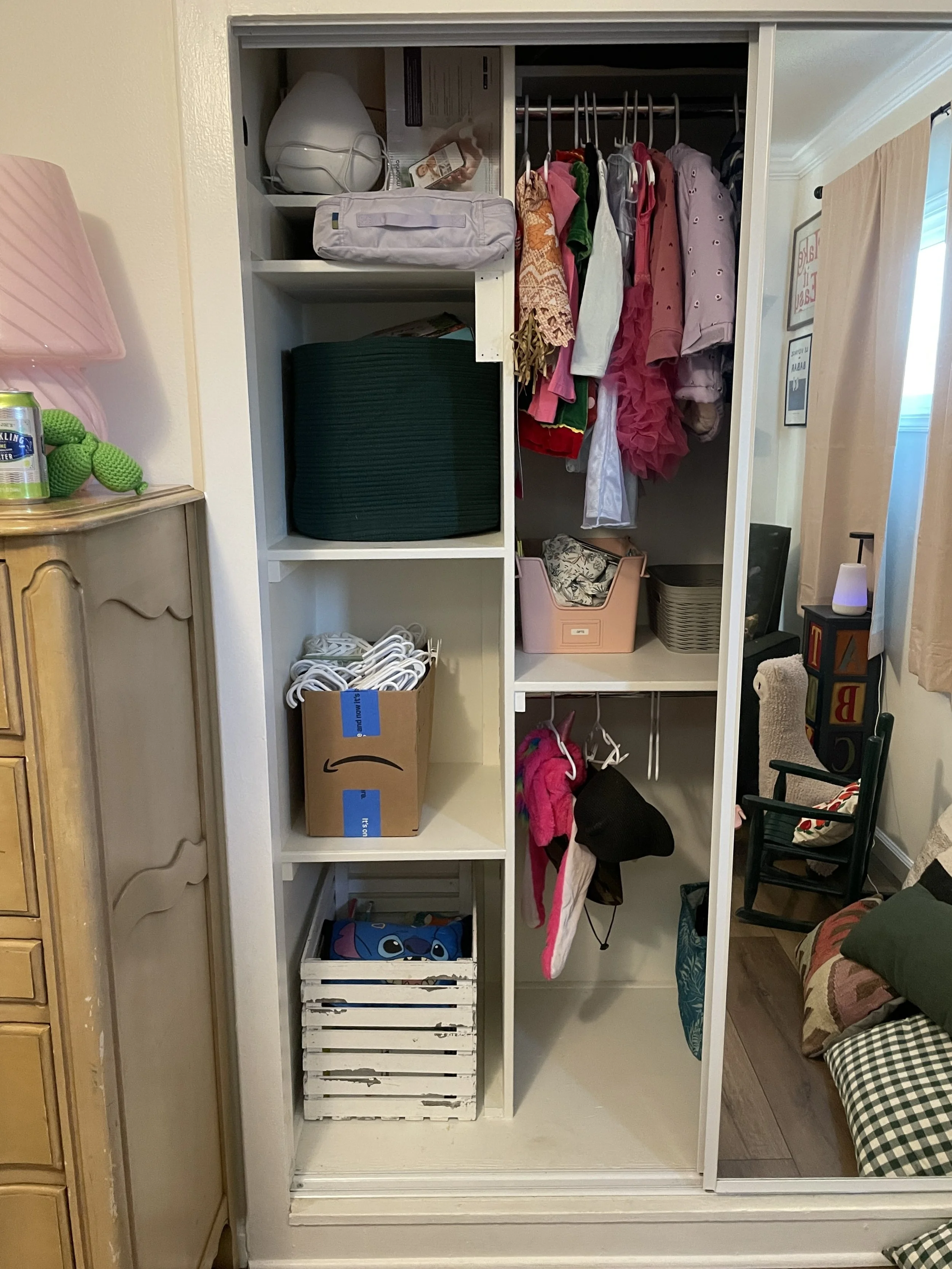 Inside a closet with various clothing items on hangers, storage boxes, and shelves holding miscellaneous items.