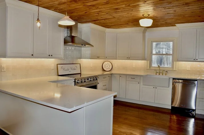 Modern kitchen with white cabinets, a wooden ceiling, a window above the sink, and stainless steel appliances.