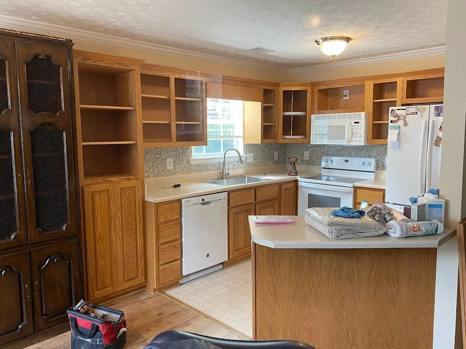 Kitchen with wooden cabinets, white appliances, a window above the sink, and various items on the counter.
