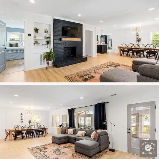 Living room with a black brick fireplace, wall shelves, a flat-screen TV, and nearby seating area; adjacent to a dining area with a large table and chairs, featuring hardwood floors and white walls.