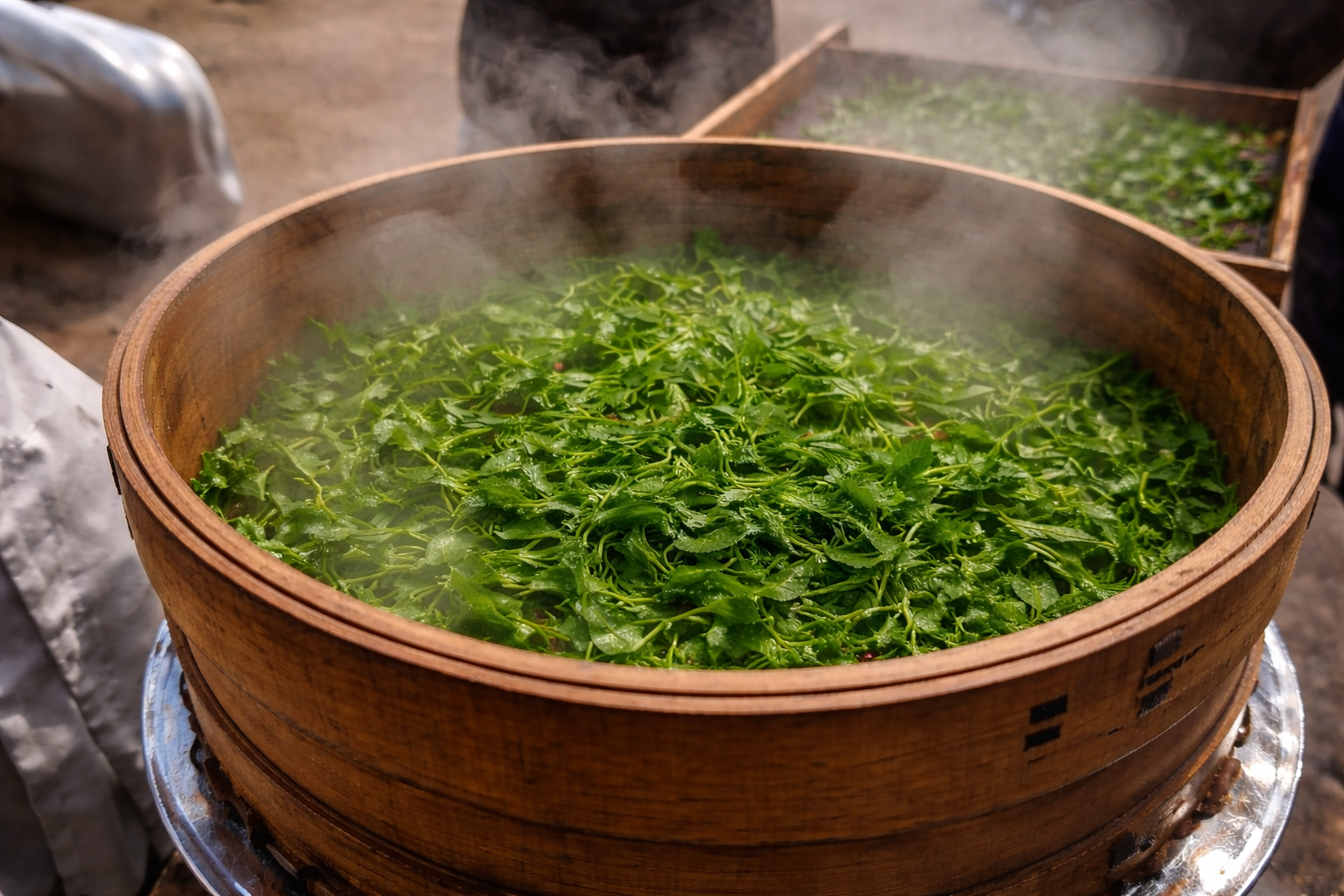 Fresh green leafy vegetables steaming in a large wooden steamer basket.