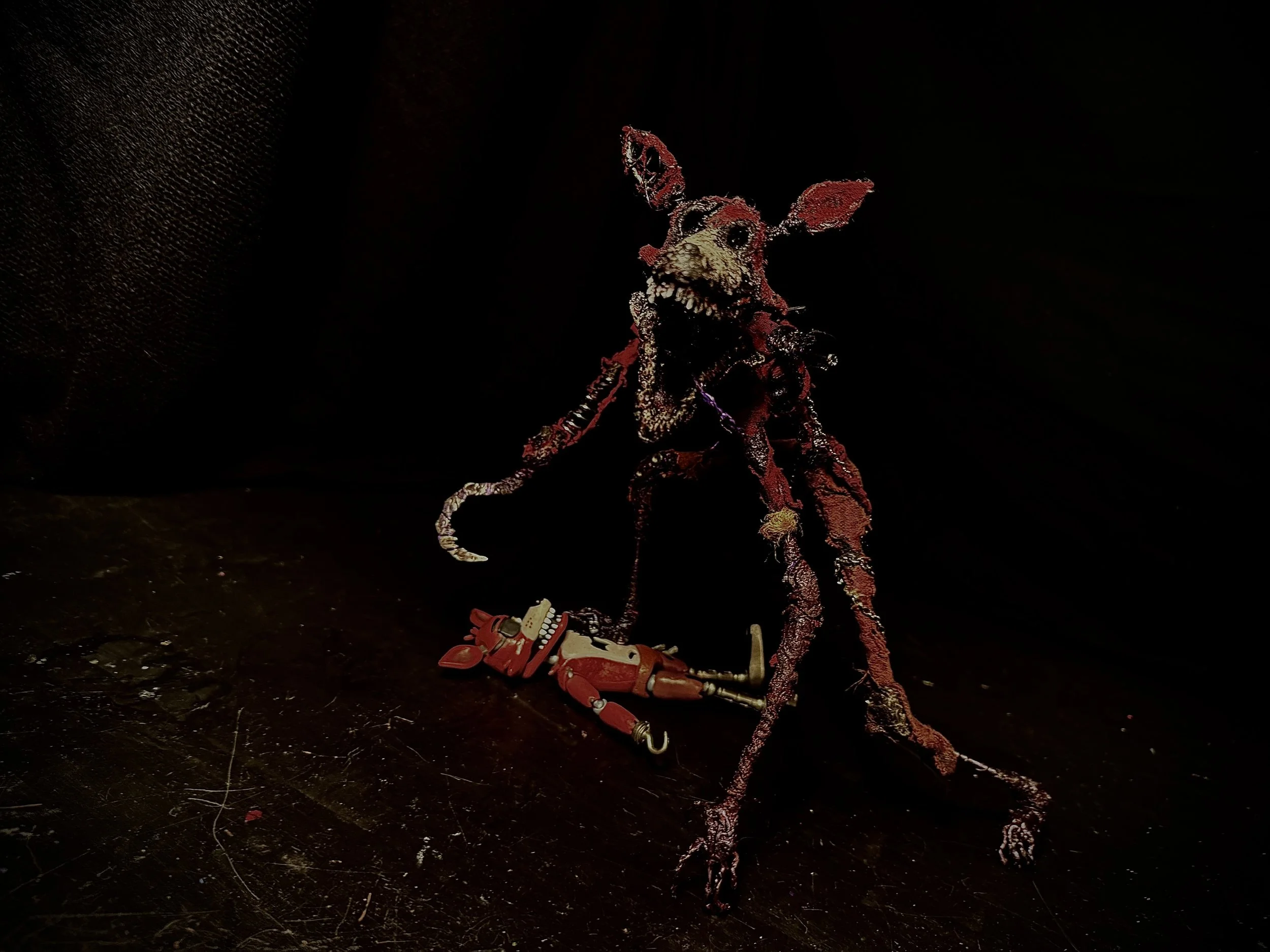Mixed-media sculpture of a rat with a robotic arm, standing on a dark floor with a black background.