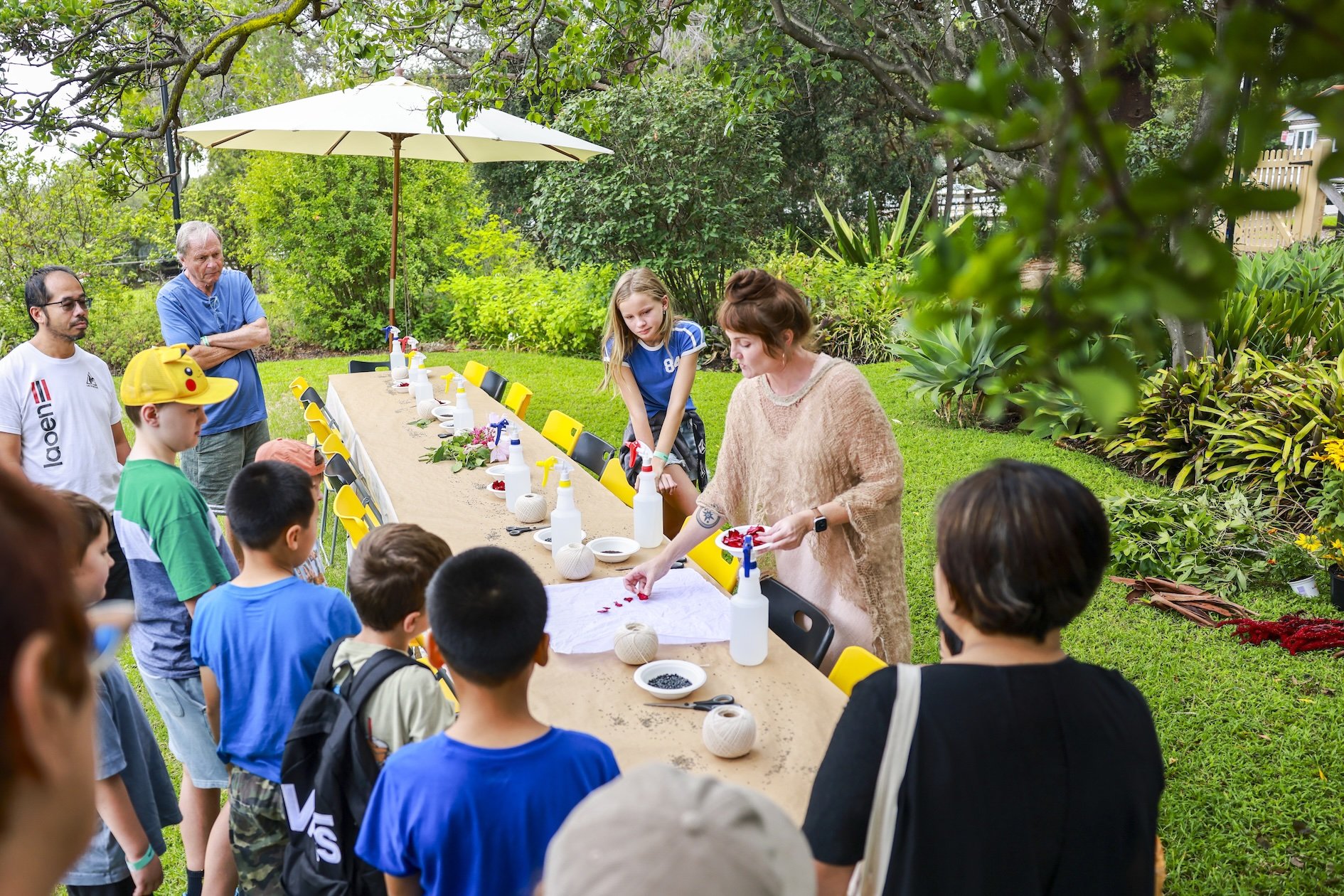 Woman laying rose petals on a bandana surrounded by children and adults watching the process