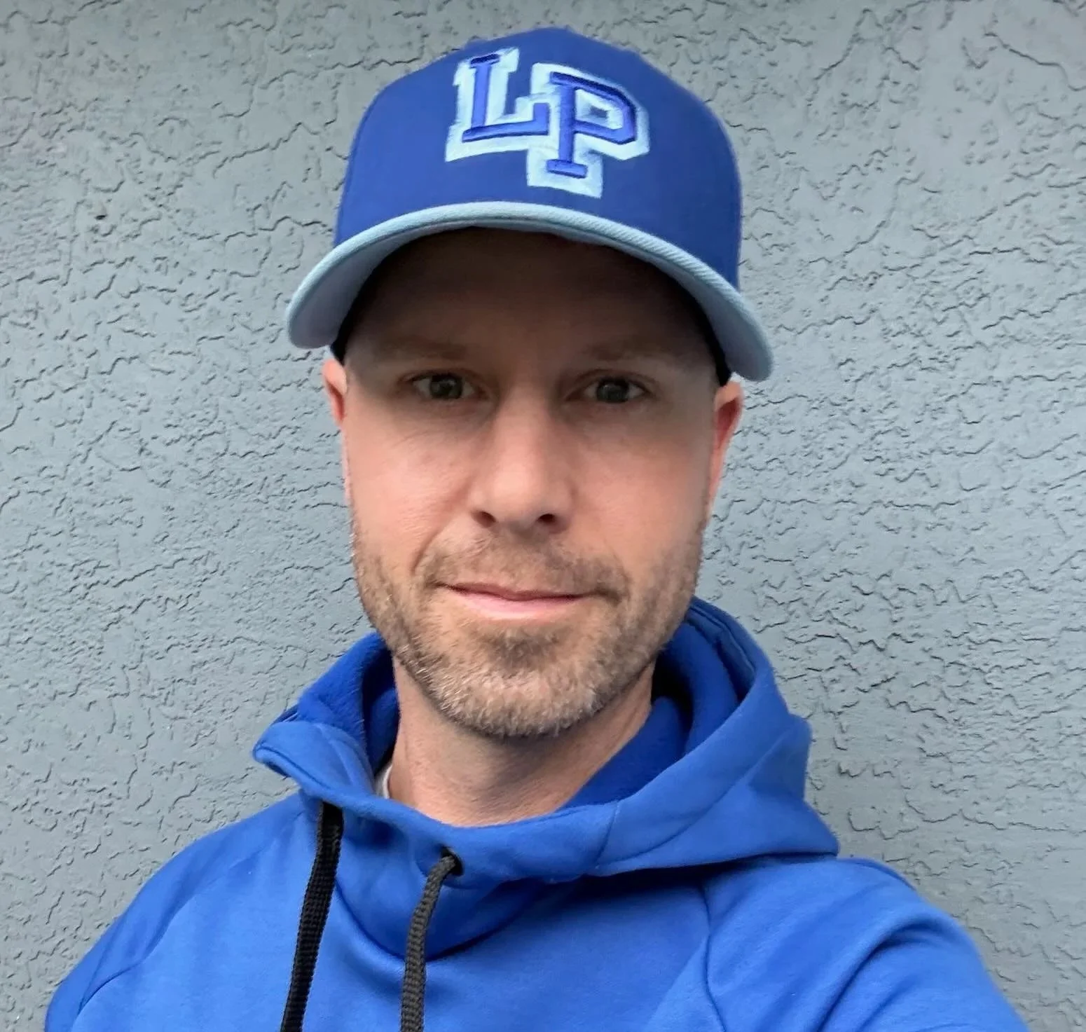 Graham Campbell wearing a blue baseball cap with white and light blue accents and a blue jacket with a black zipper.