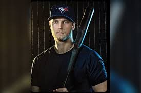 Young man wearing a baseball cap holding a baseball bat in a dimly lit room