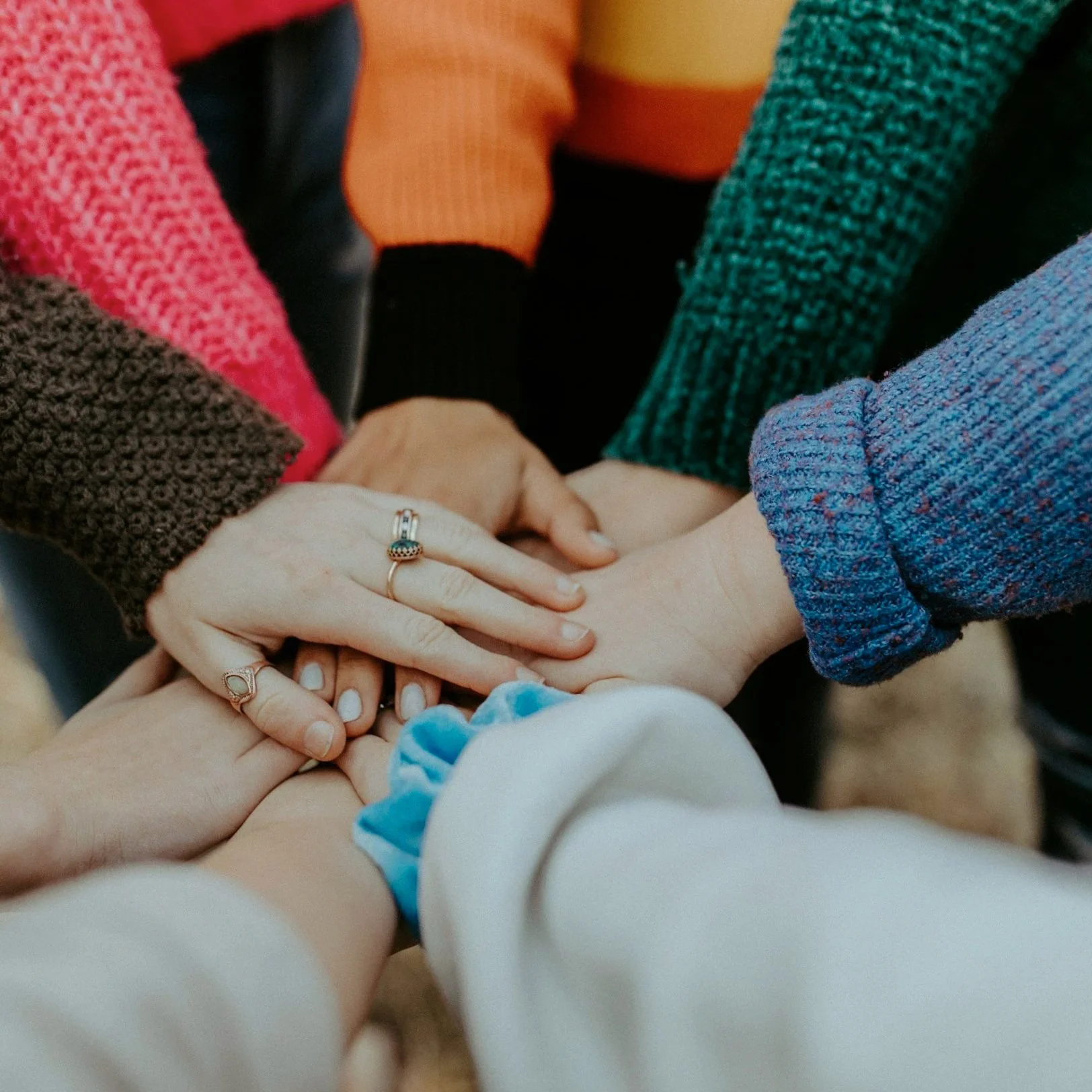 Multiple hands of diverse individuals stacked together, symbolizing unity and teamwork.