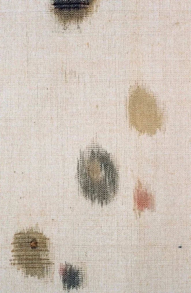 Close-up of a textured fabric with various small stains and spots of different colors and shapes.