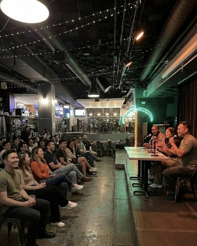 Comedians performing stand-up comedy on stage at a comedy club with an audience watching and laughing.