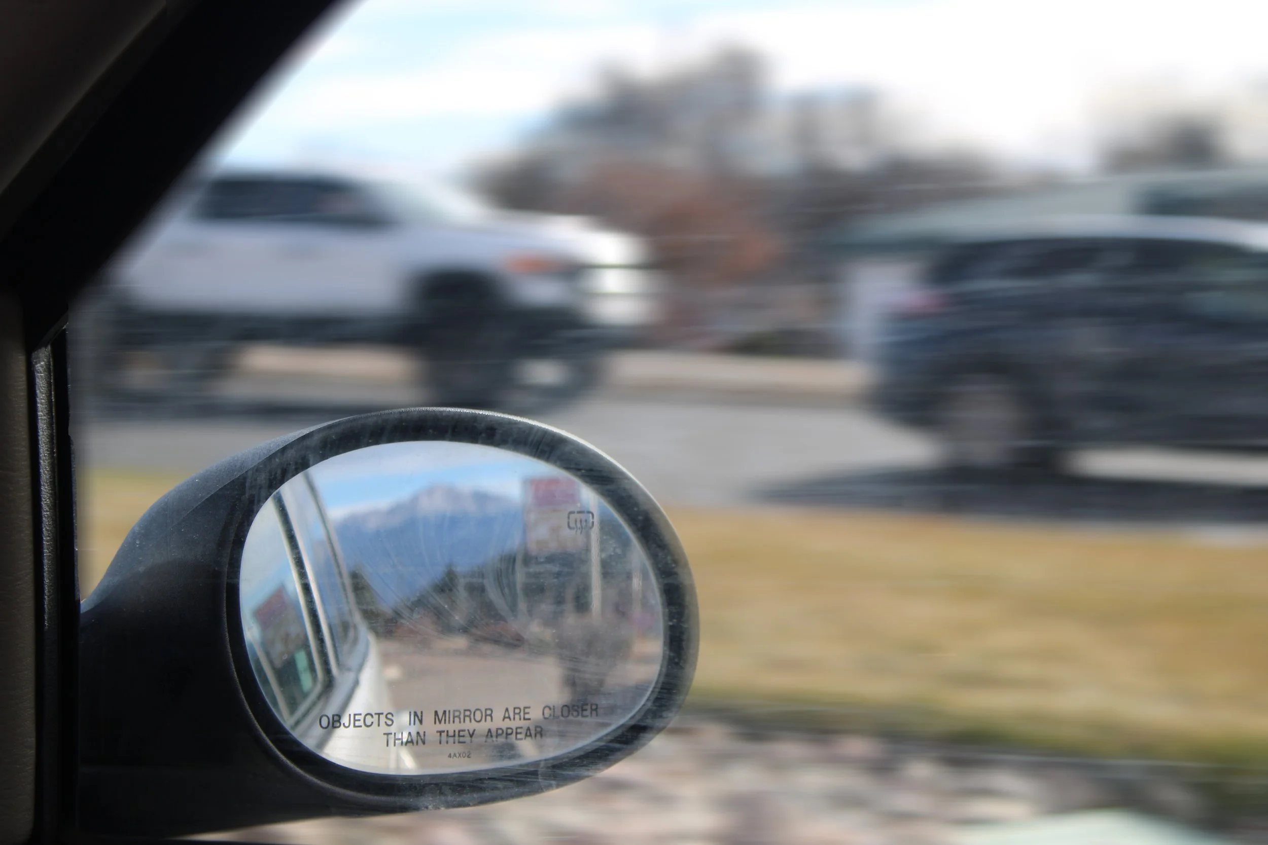 A rearview mirror seen from inside the car, and moving vehicles flying past behind it.