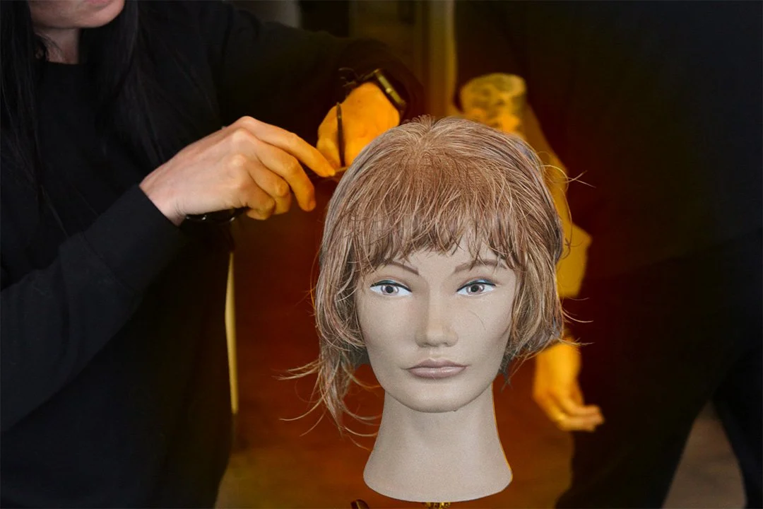A hair stylist at Starling Salon cuts her mannequin's hair with a razor.