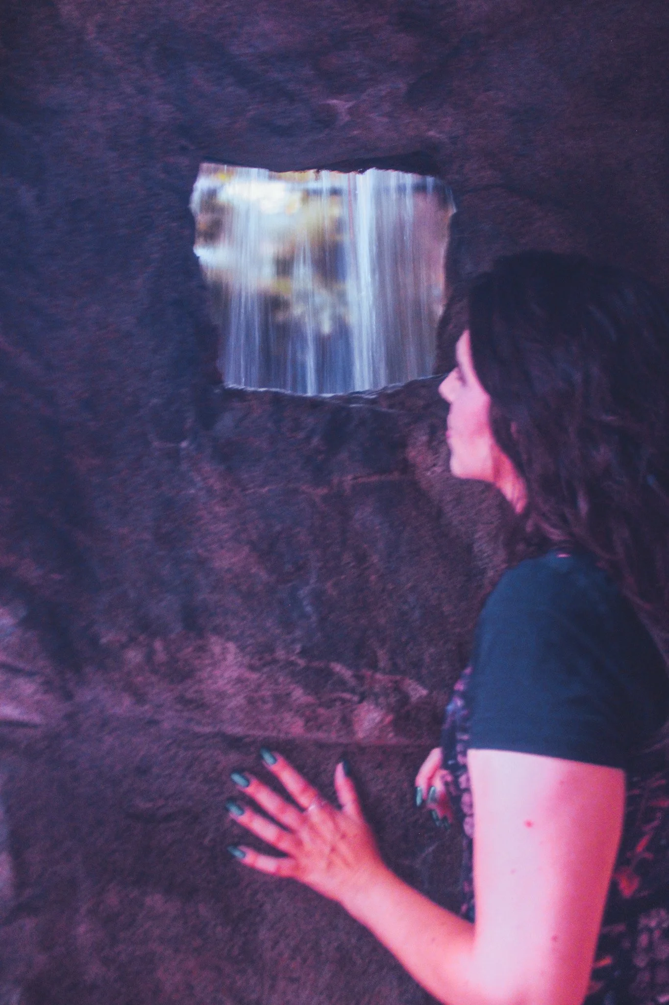 Emma watches a waterfall from behind it.