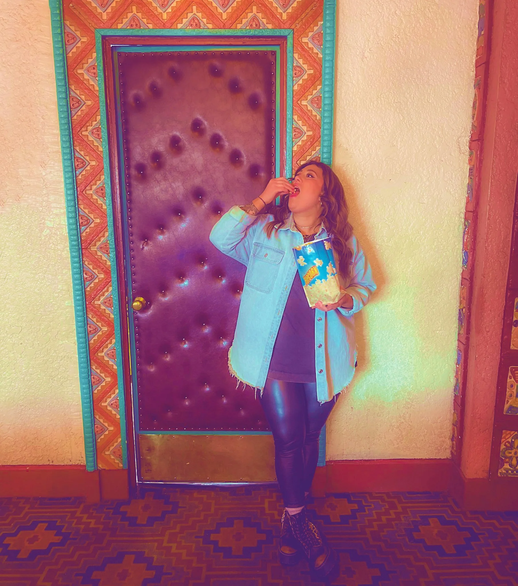 Megan Brockman eats popcorn at the Mayan Theater, resting against the colorful decor.