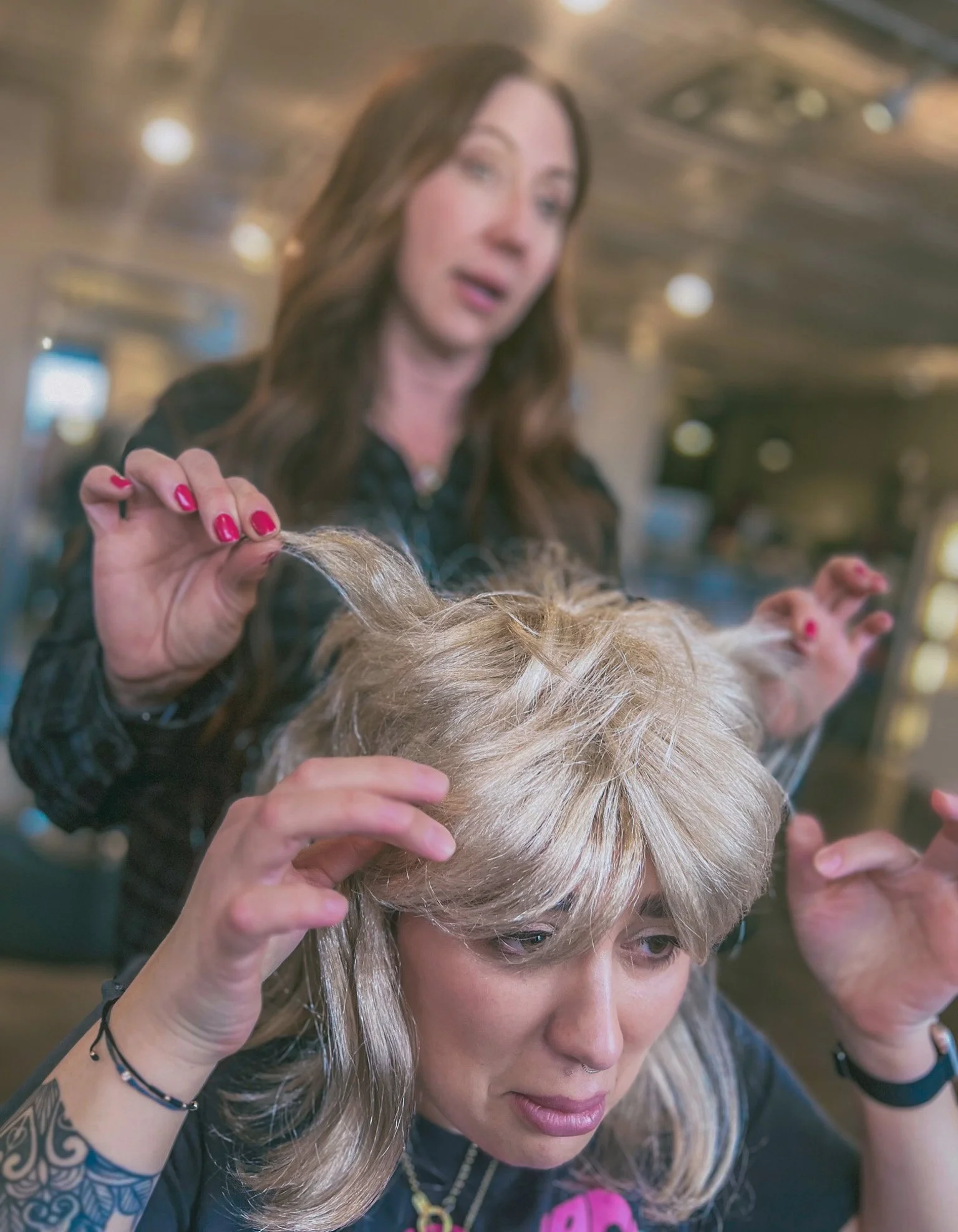 A salon professional shows their guest the options after a bad haircut.
