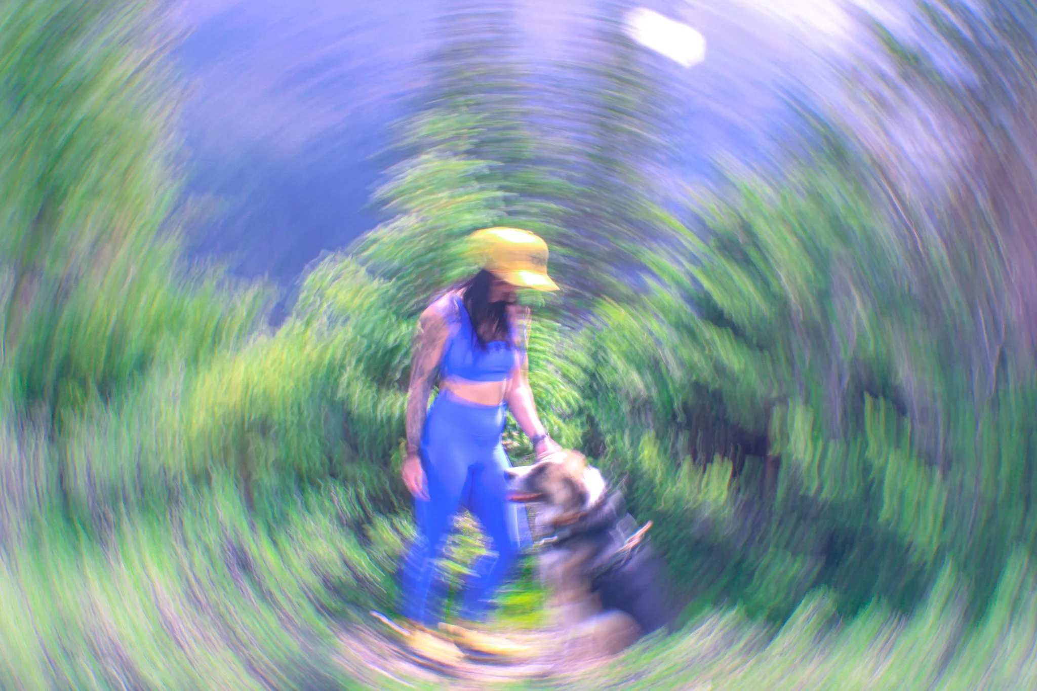 Kate Davis stands next to a mountain trail with her dog, Moose. The image is edited to look like a swirl.