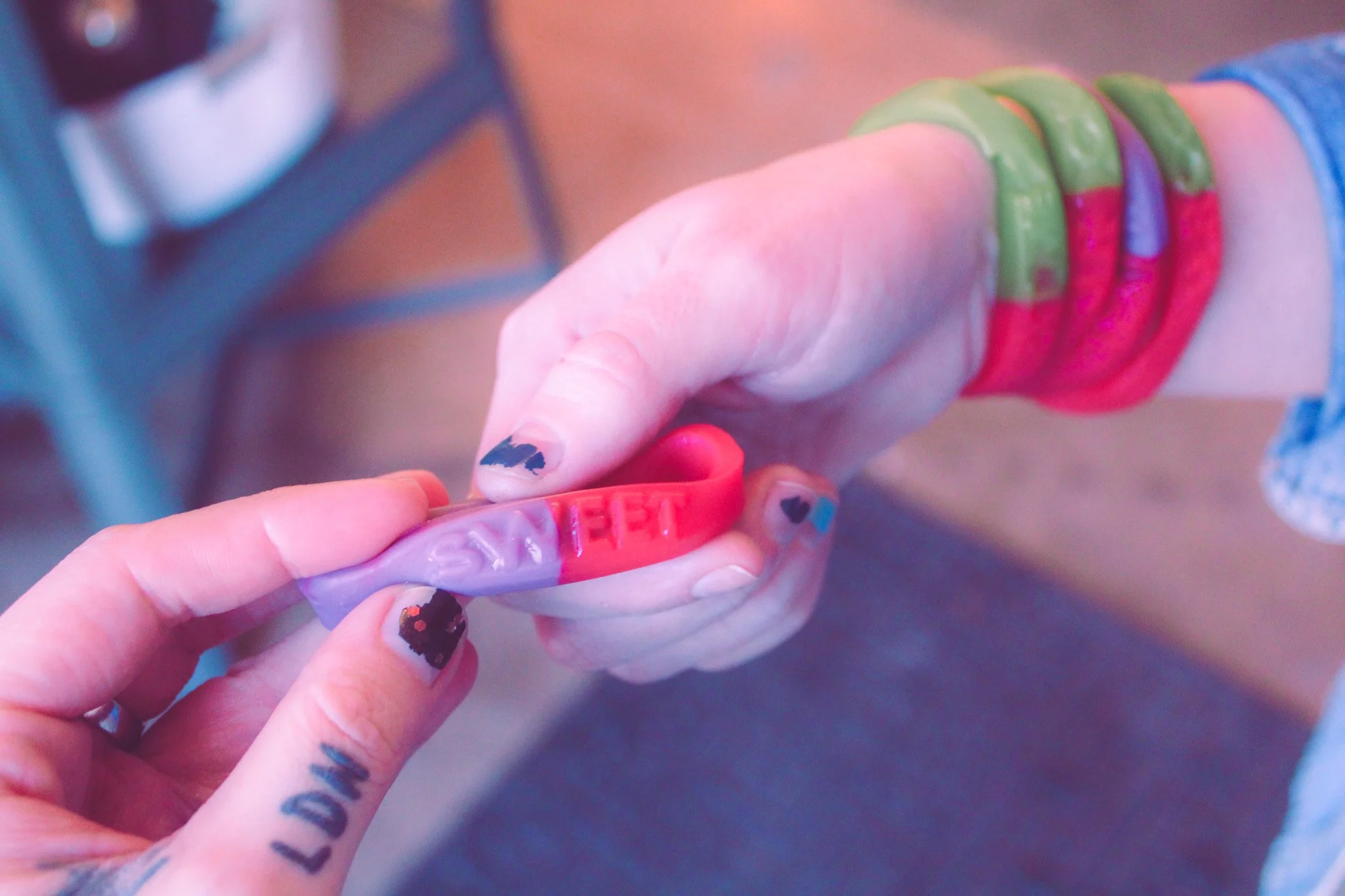 Two hands exchange a candy bracelet with the word "sweet" written across it.