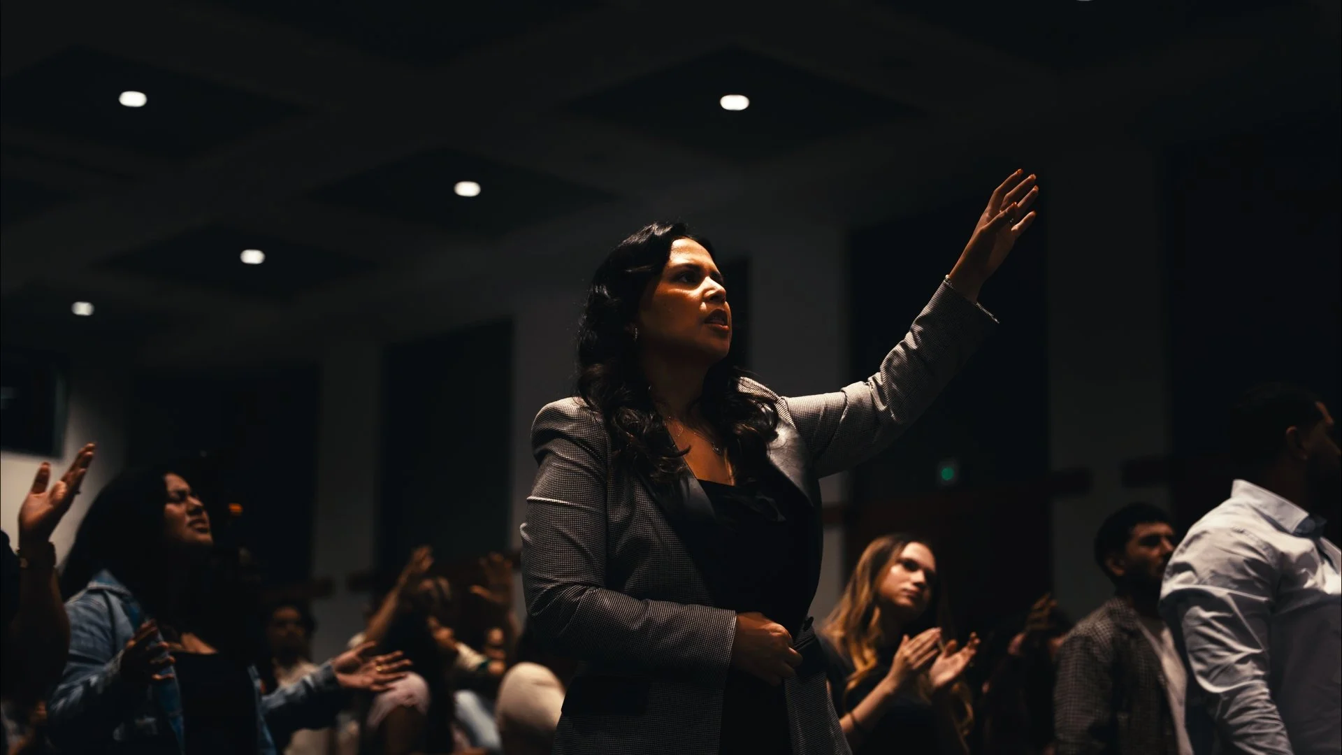 Woman raising her hand during a conference or seminar with other attendees around her.
