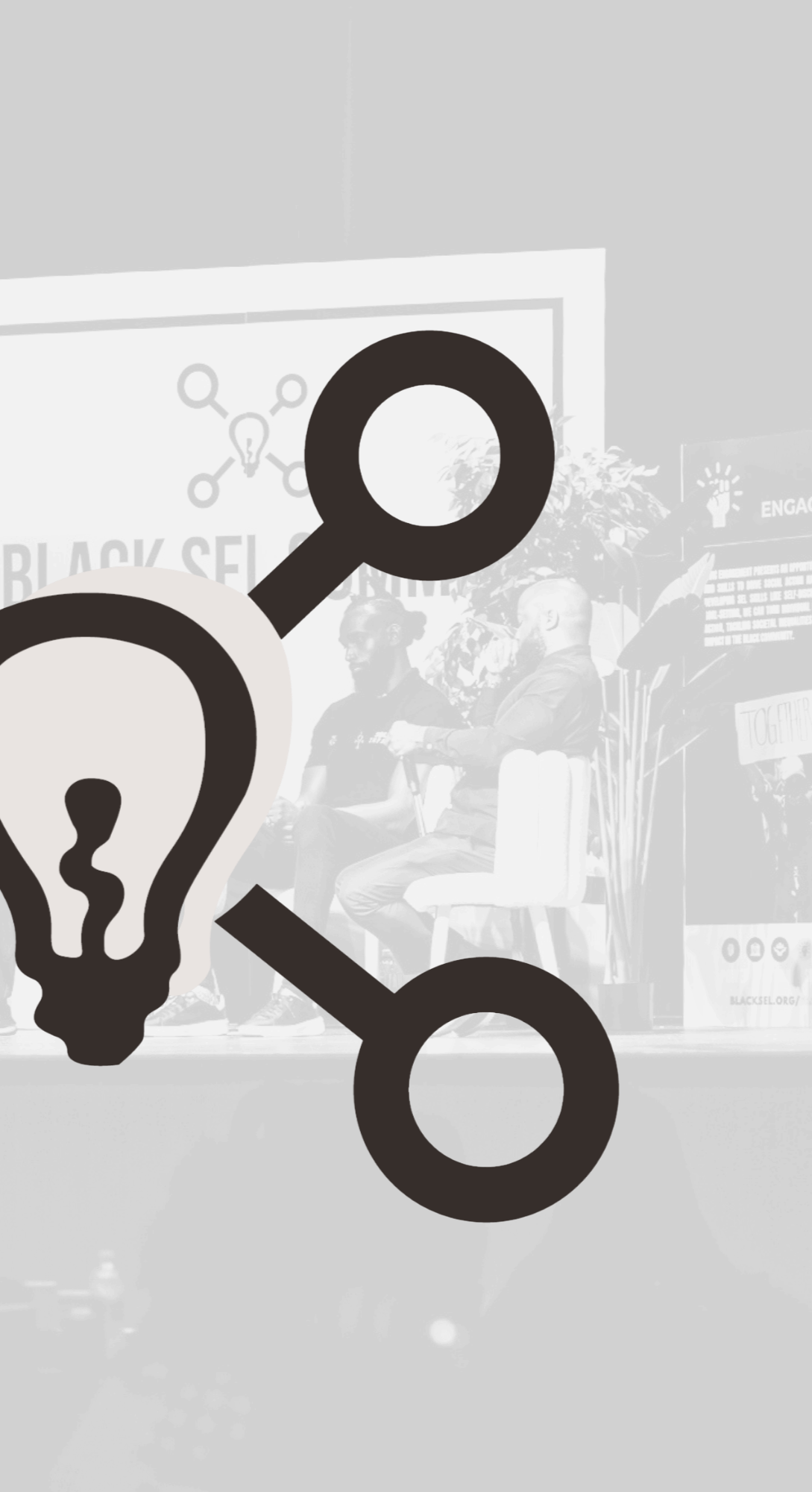 A black and white photo of two men seated on stage, participating in a panel discussion. The stage is decorated with plants and various signs, including a sign that says "Together." A large light bulb icon overlays the image.