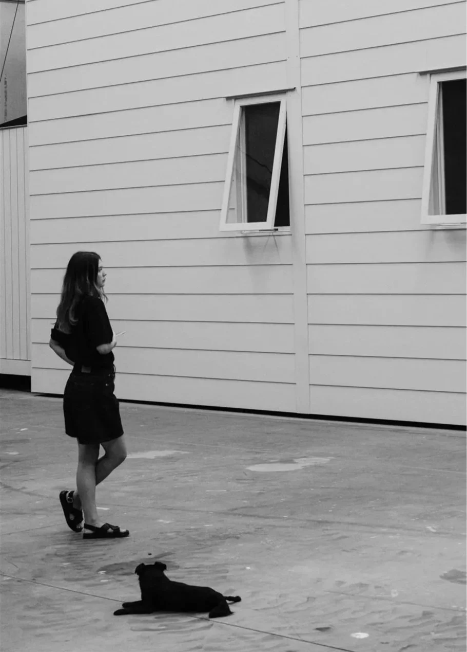 GOODARCH STUDIO founder Mackenzie Goodman outside a weatherboard-clad building, with a dog resting nearby