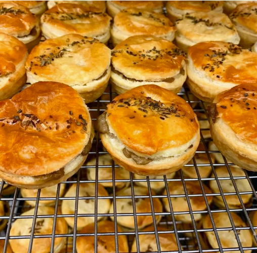 A tray of freshly baked savory cheeseburger sliders with melted cheese and black sesame seeds on top, cooling on a wire rack.