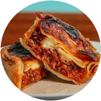 Close-up of a lasagne pie cut in half, showing ingredients inside.