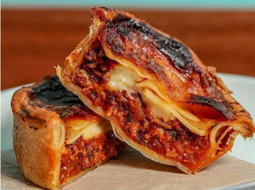 Close-up of a lasagne pie cut in half, showing ingredients inside.