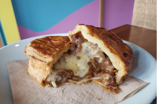 Close-up of a steak and cheese pie with a flaky crust and gooey filling