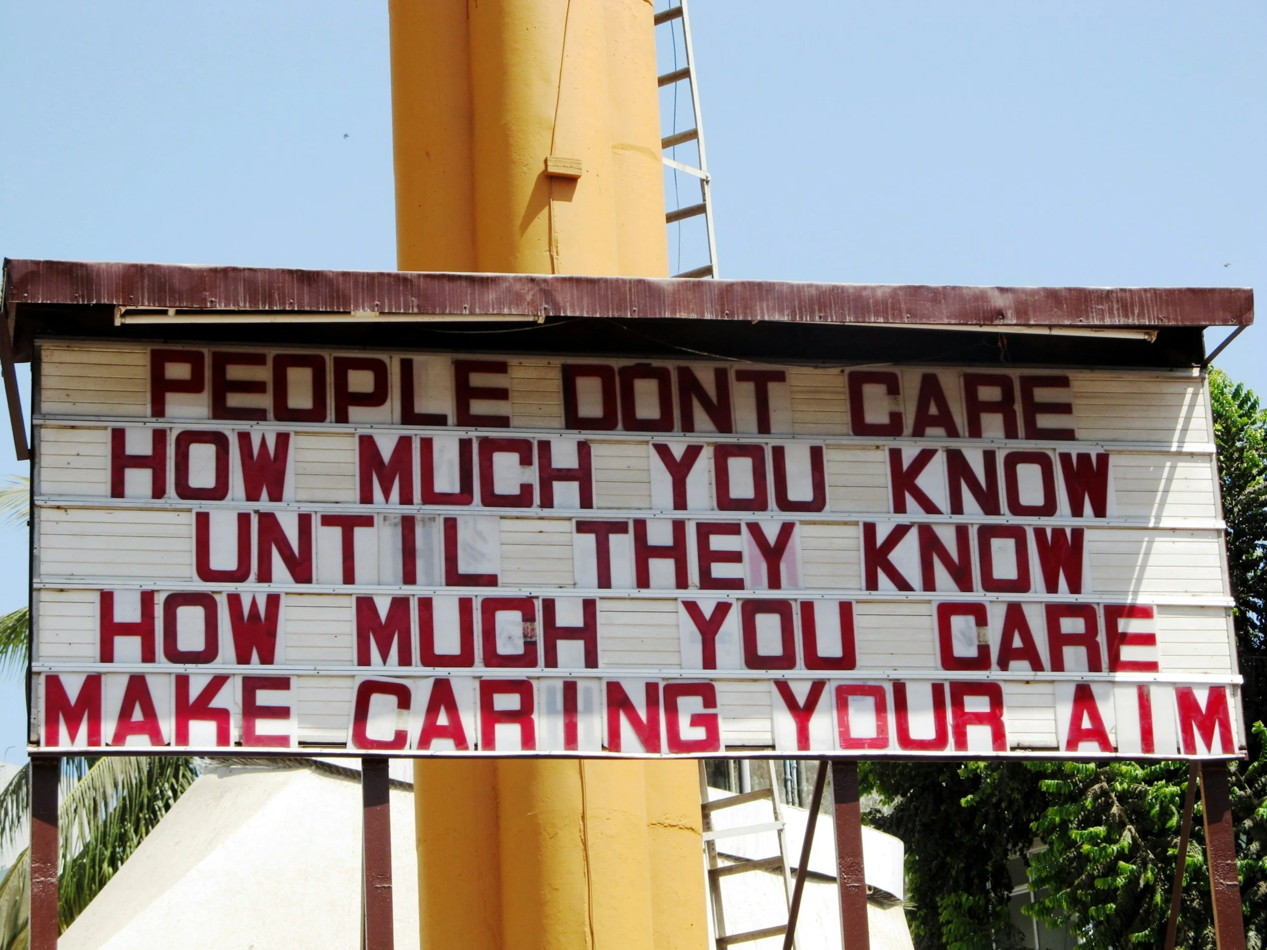 Outdoor sign reading "People don't care how much you know until they know how much you care," symbolizing empathy, compassion, and emotional connection.