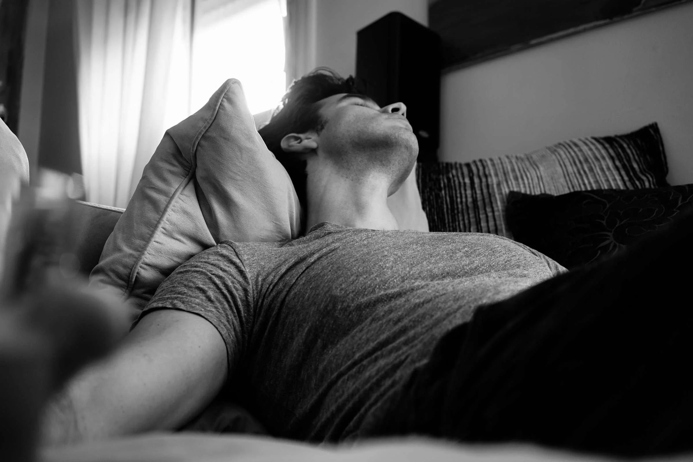 Person resting on a couch in a quiet room, illustrating the importance of sleep, rest, and restoring healthy routines for mental health and emotional balance.