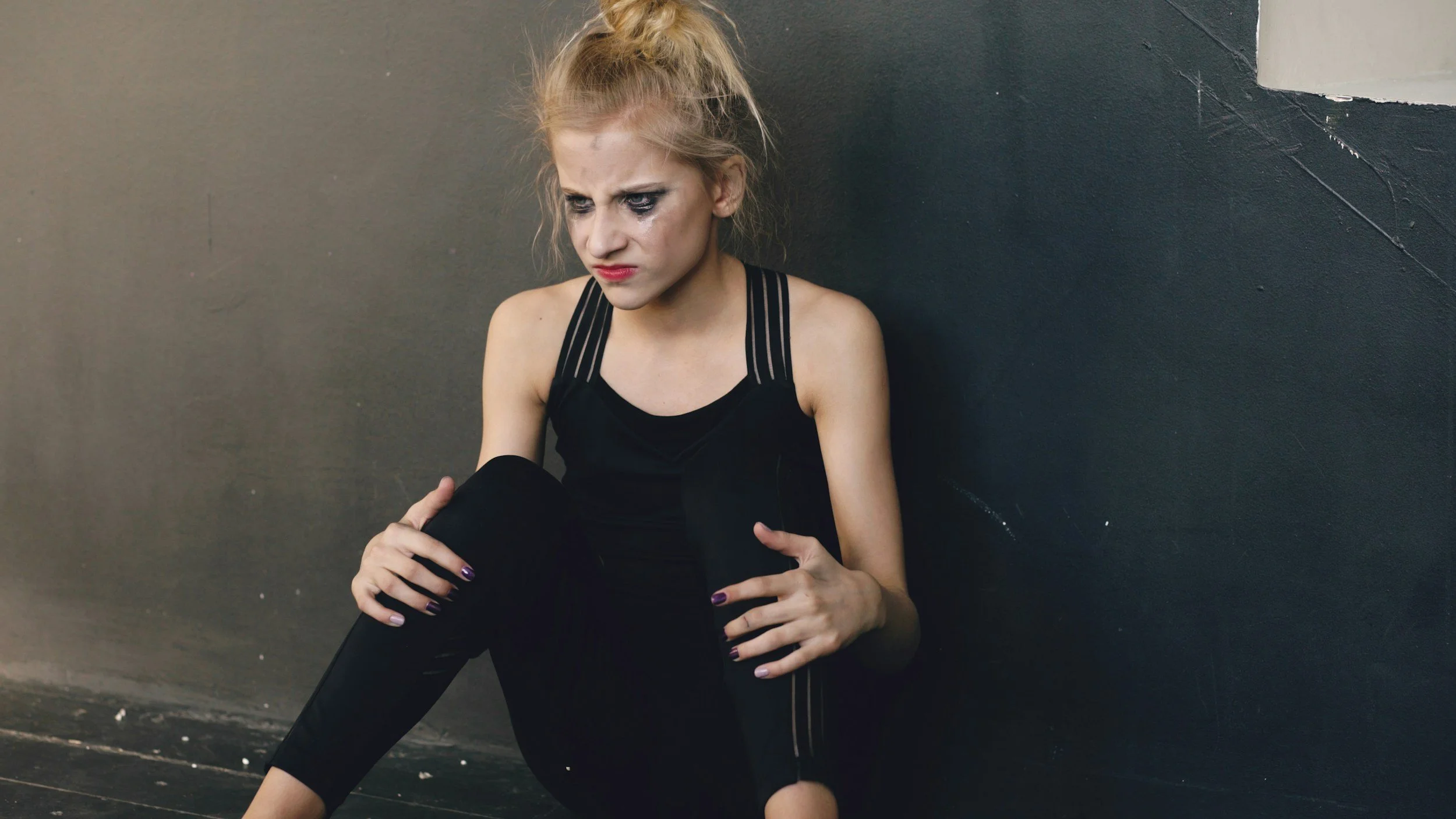 Young woman sitting alone looking down thoughtfully, representing feelings of shame, self-doubt, and internal criticism.