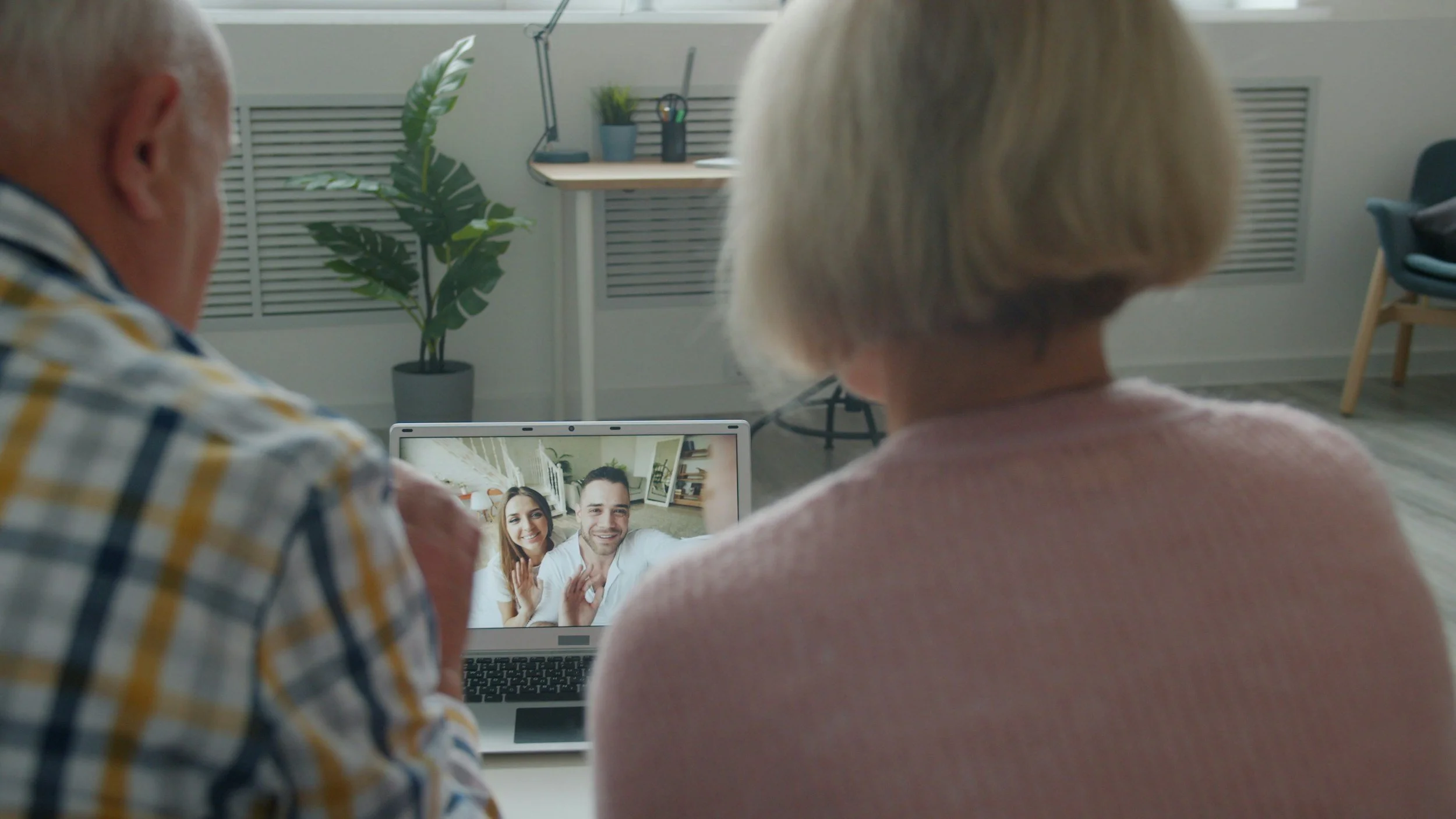 Older couple video chatting with loved ones on a laptop, symbolizing staying connected to reduce loneliness and support mental health.