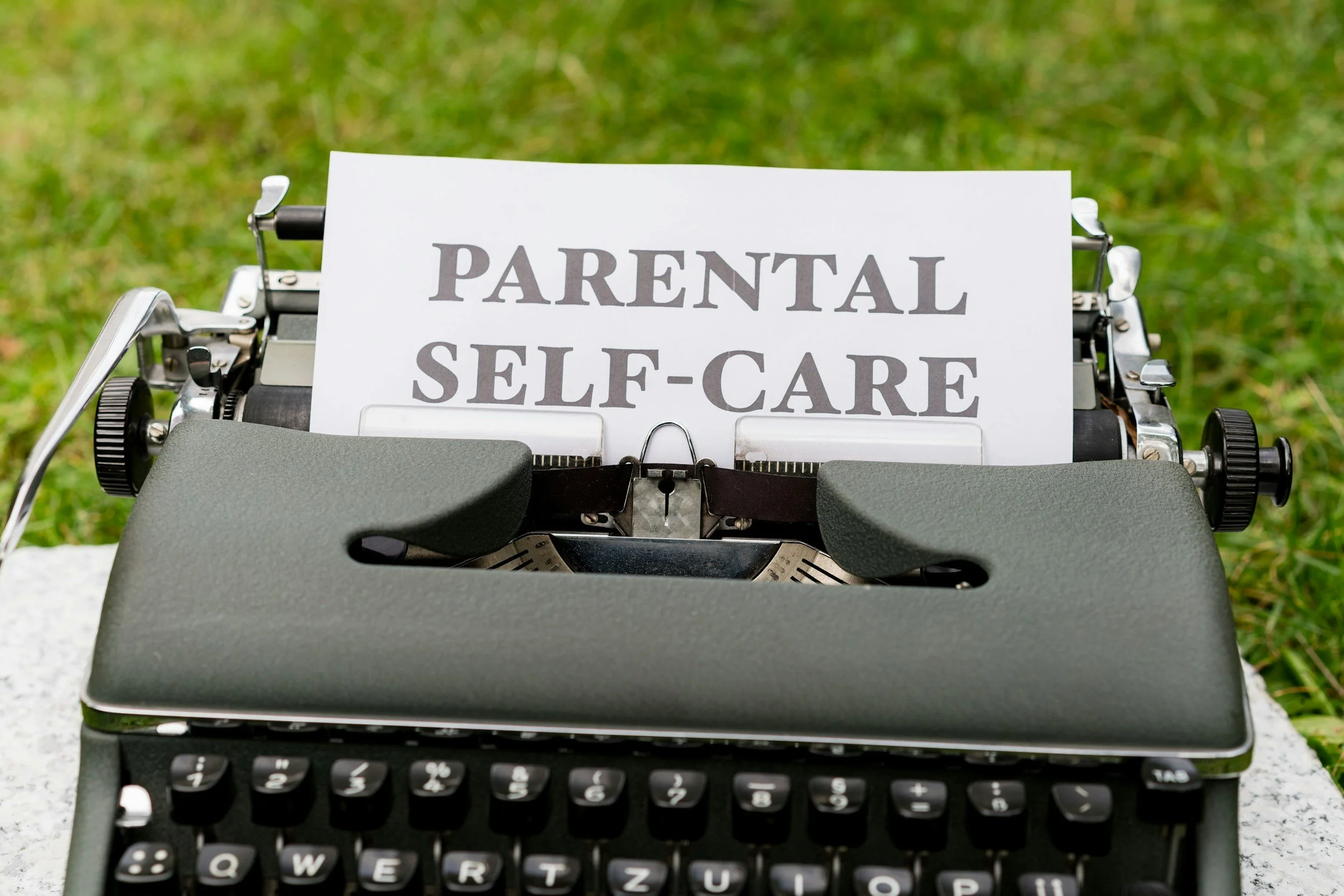 Typewriter displaying the words "Parental Self-Care" symbolizing the importance of self-care, emotional wellness, stress management, and mental health support for mothers.