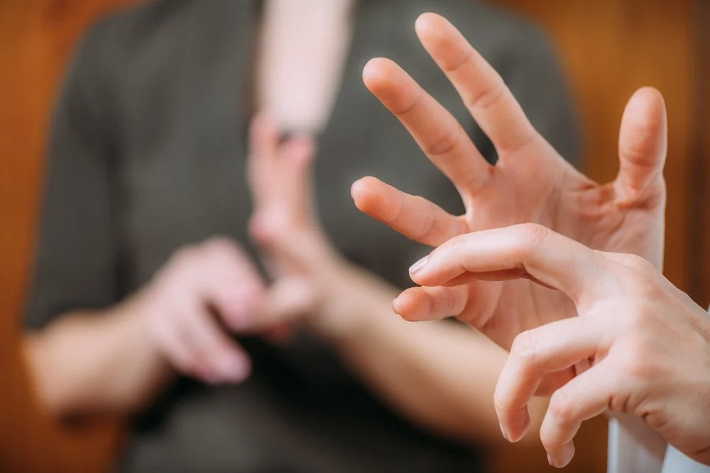 Two people having a sign language conversation, focusing on their hands and fingers.