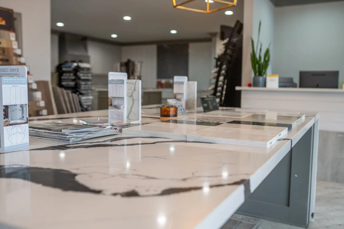 A marble countertop display in a flooring showroom with color samples and brochures, in a modern store interior.