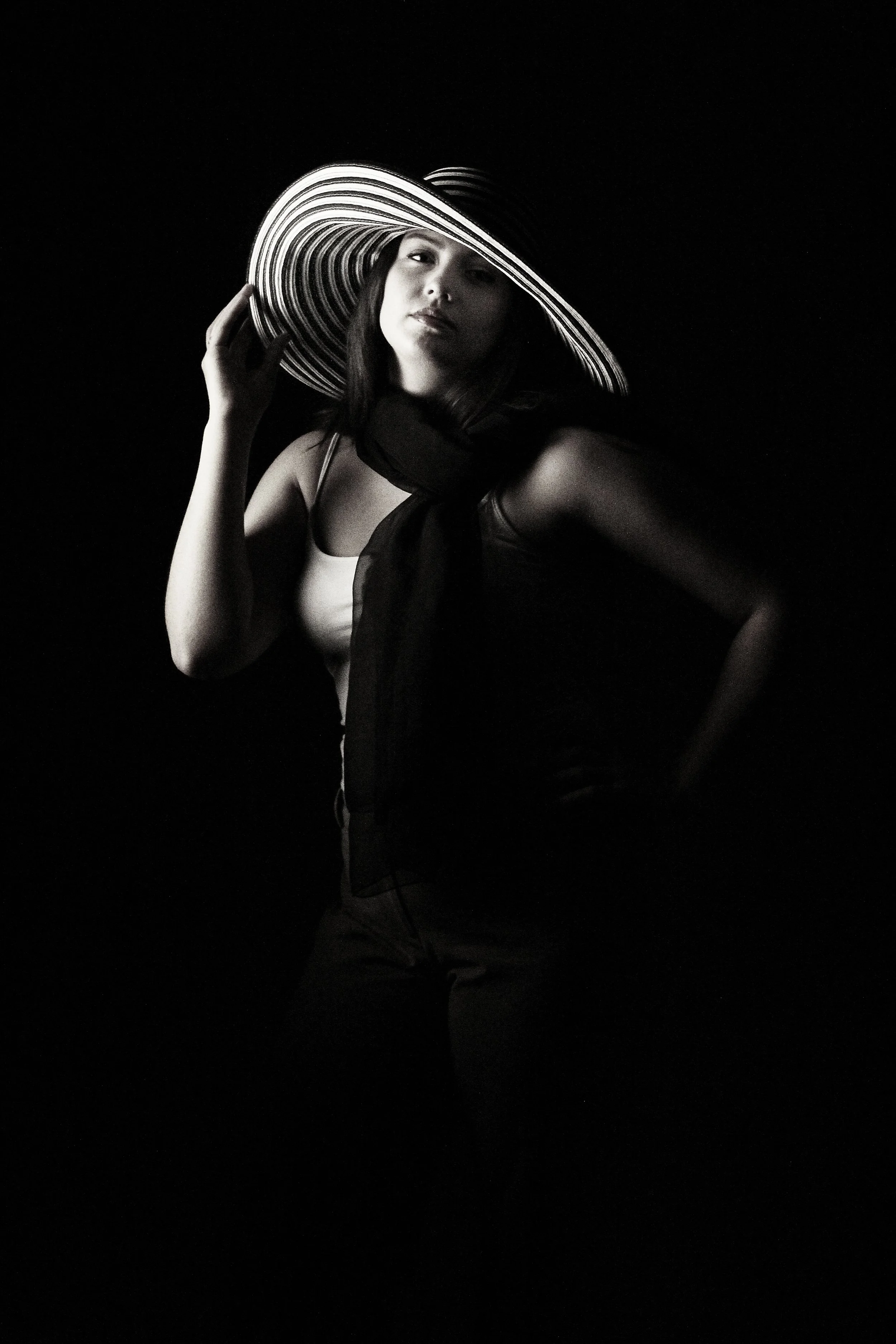 Dramatic studio lighting model in B&amp;W with large striped hat