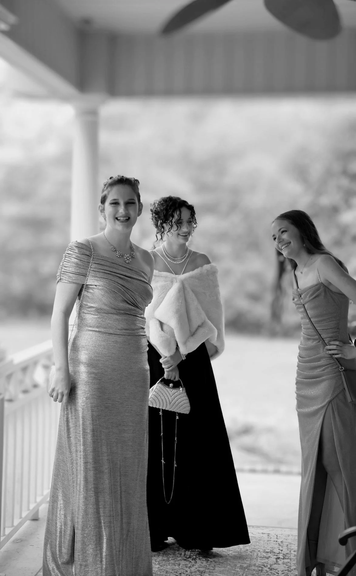 Candid portrait Senior Prom Dinner Event Three women in formal dresses standing and smiling outdoors during daytime.
