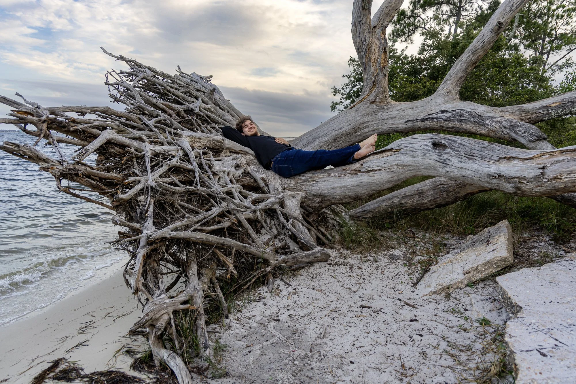 Gulf Breeze senior portrait session — senior relaxing on driftwood along the Gulf Coast shoreline, natural light photography
