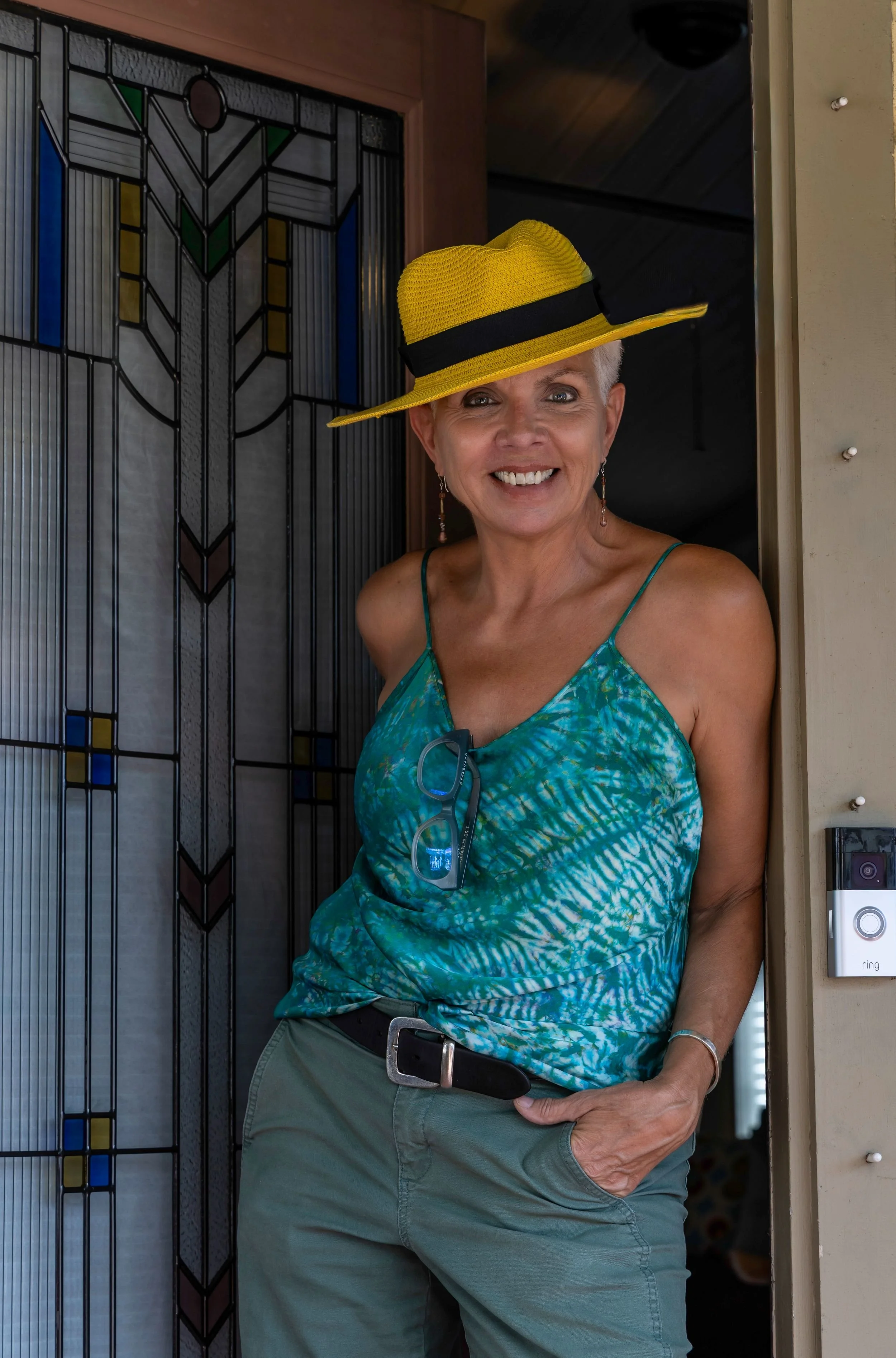 Branding portrait of Cathy Griffin in yellow hat, art deco glass door