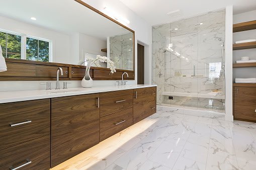 Modern bathroom with a wooden vanity, marble floor, walk-in shower with marble walls, and open shelving with towels.