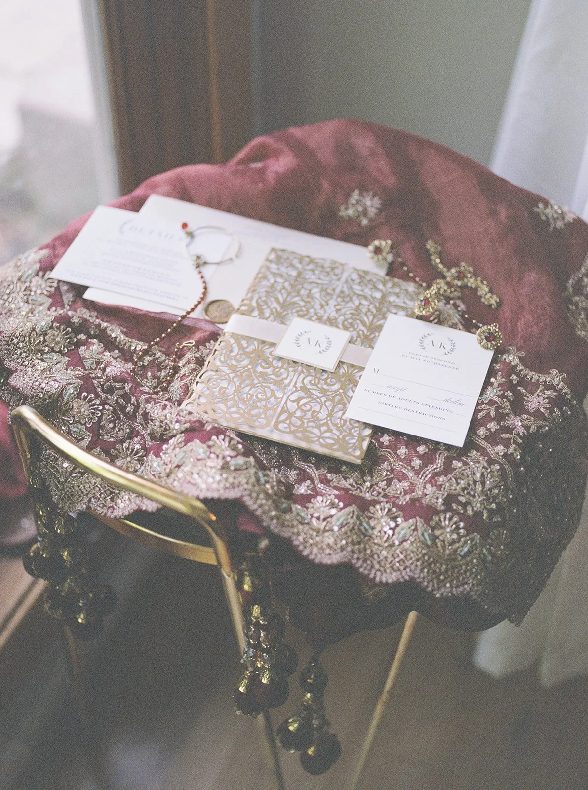 Elegant table with ornate fabric, jewelry, and invitation cards for a special event.