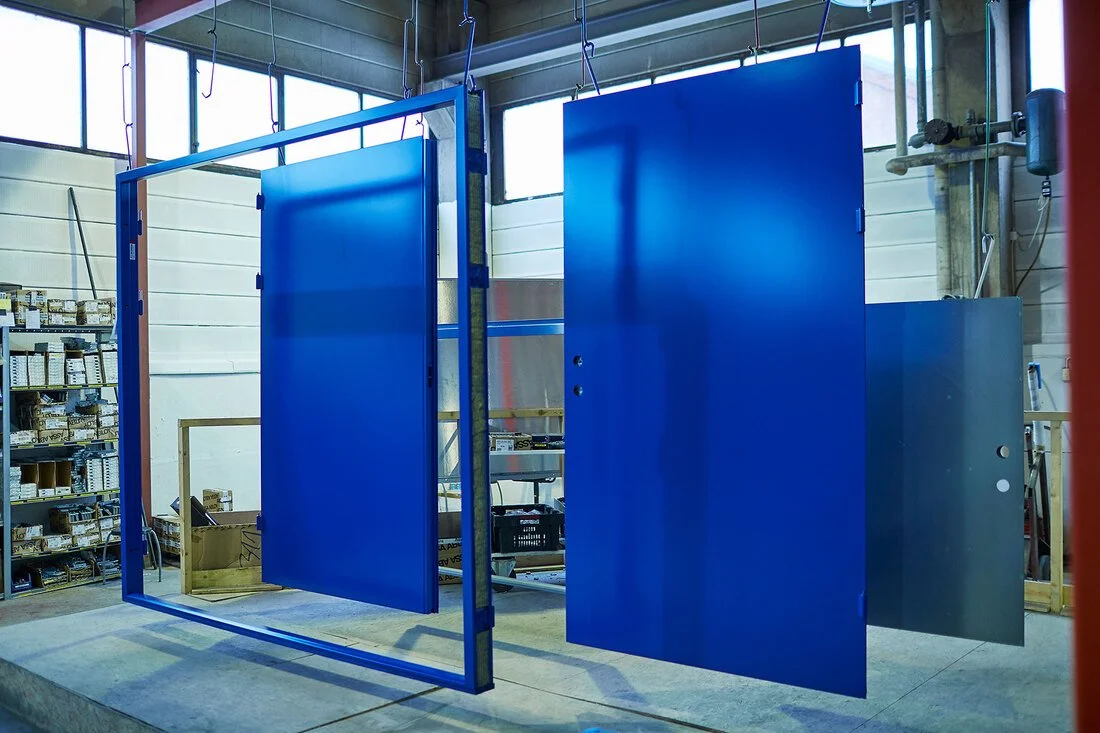 Industrial blue metal doors hanging from a ceiling in a warehouse or workshop.