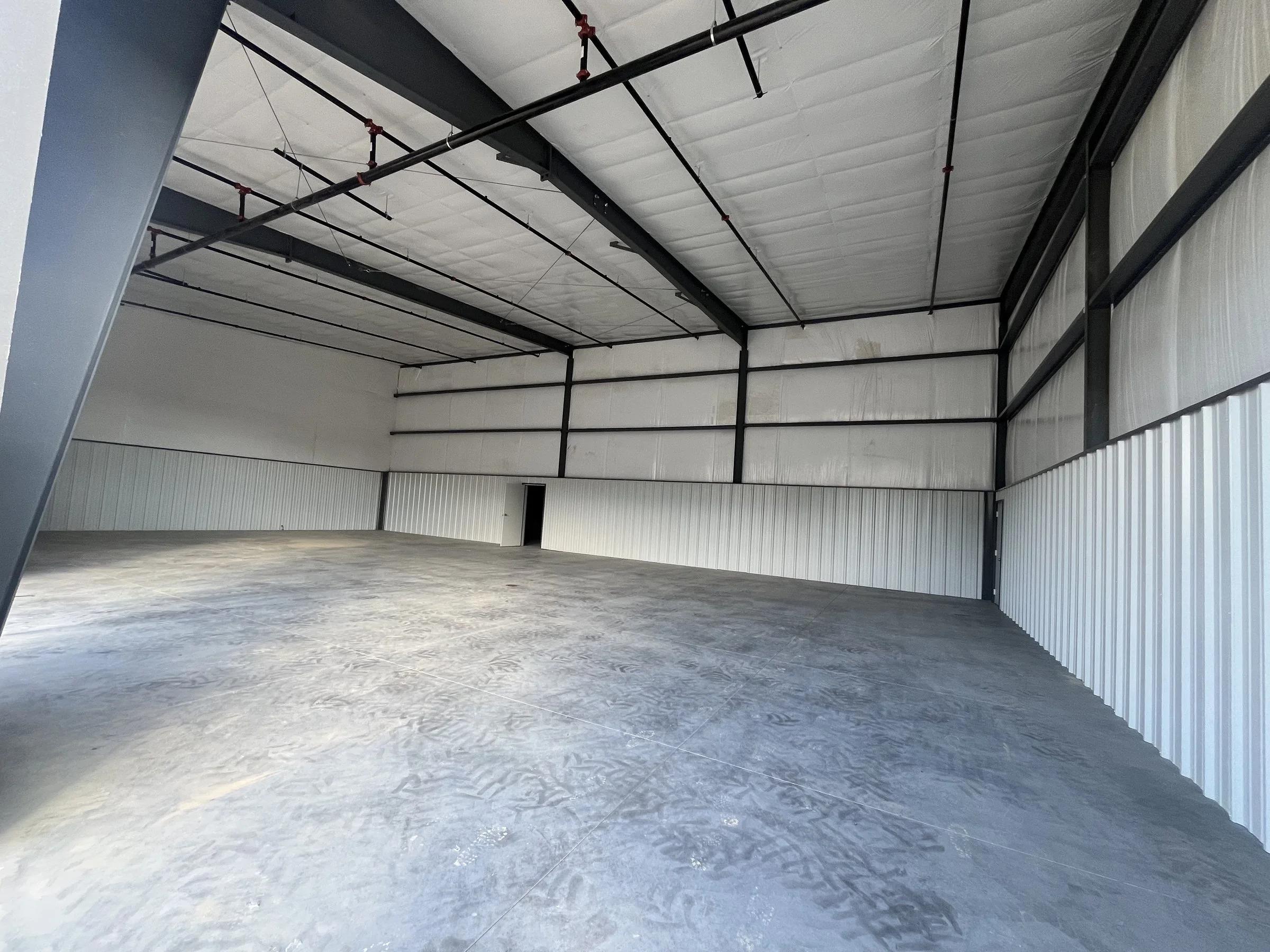 Clear-span commercial steel building interior with open floor area and insulated metal walls