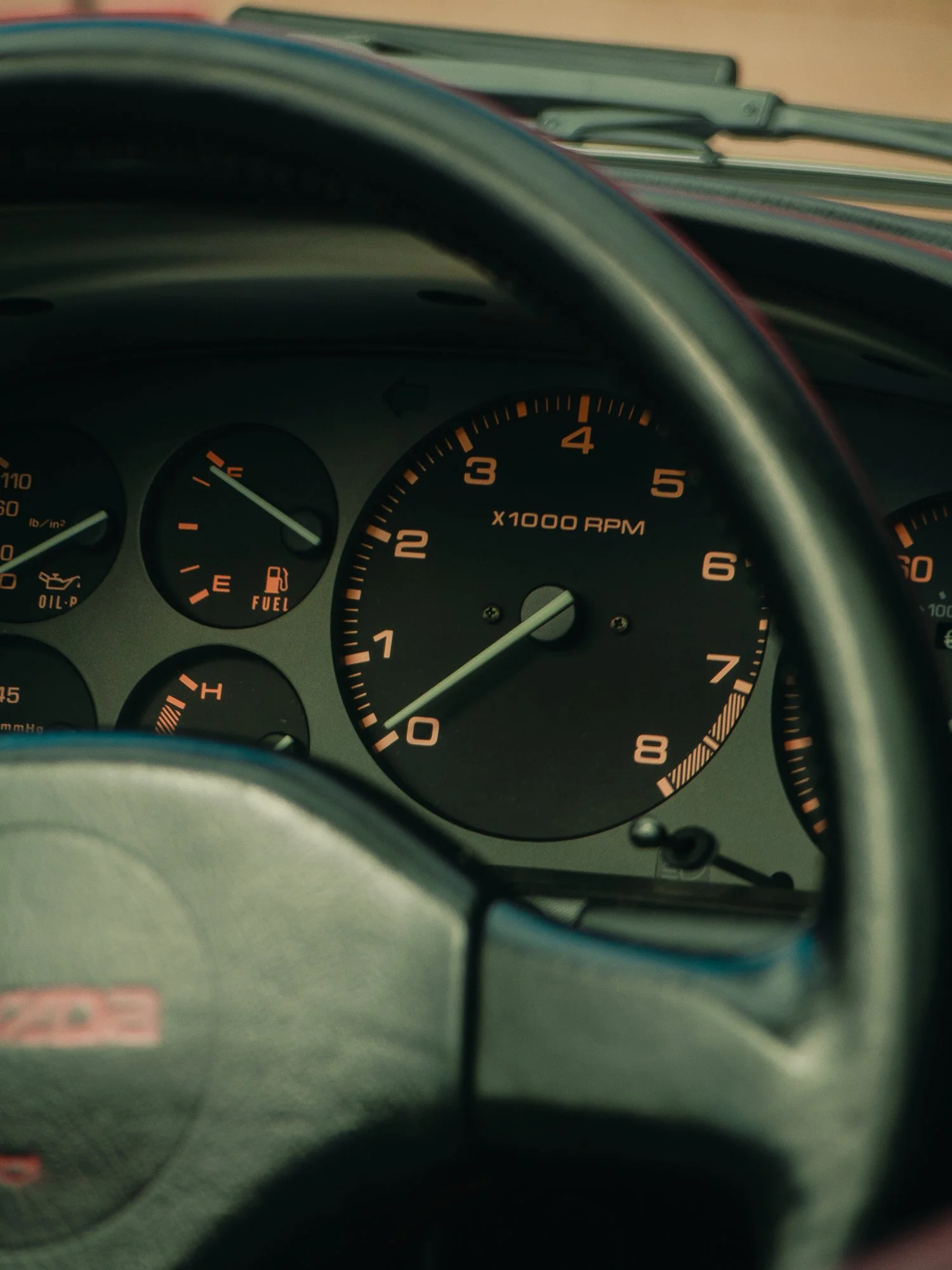 Close-up of a car's dashboard with the speedometer, fuel gauge, and tachometer visible.
