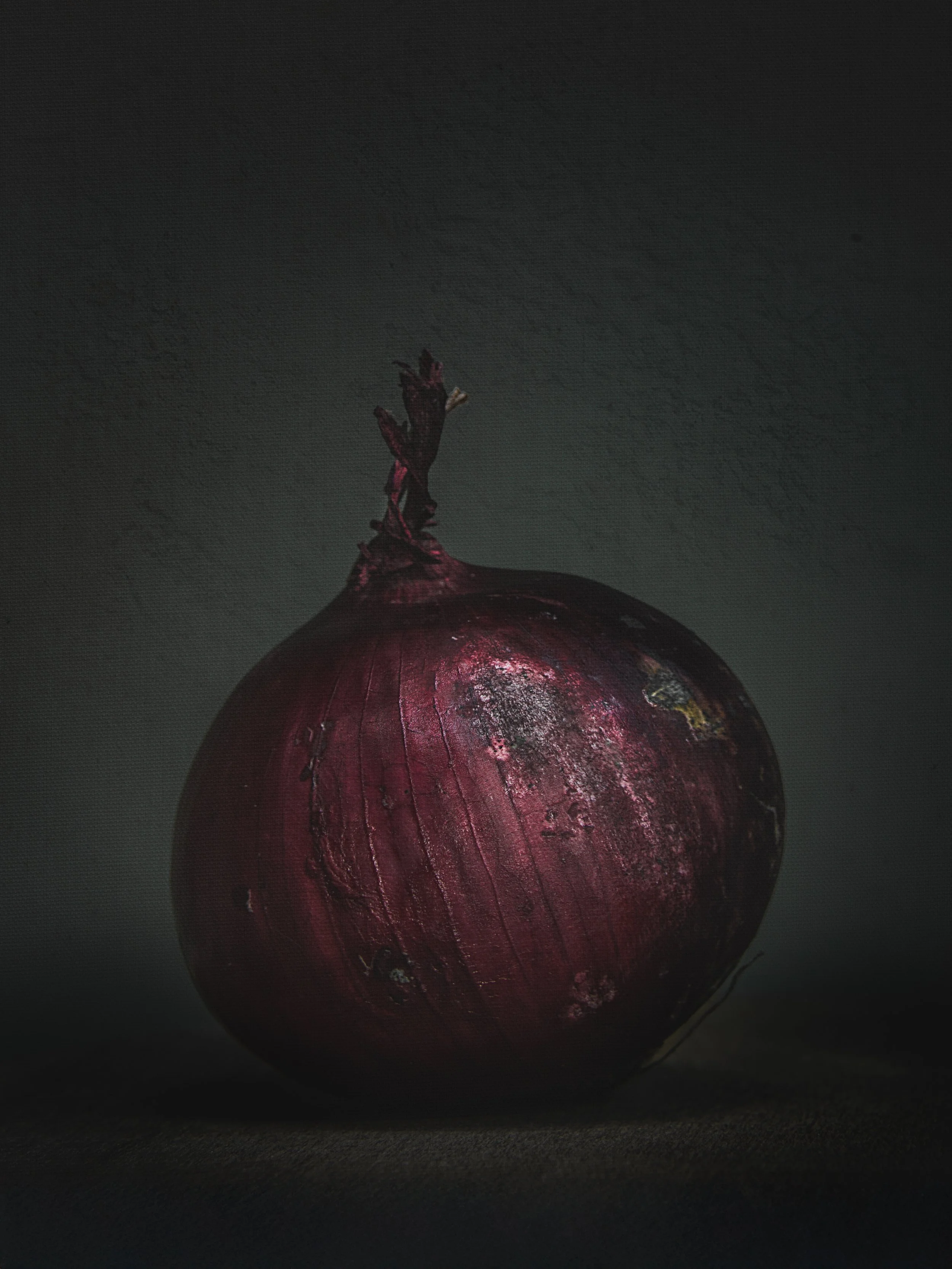 A close-up image of a single red onion with a dark background.