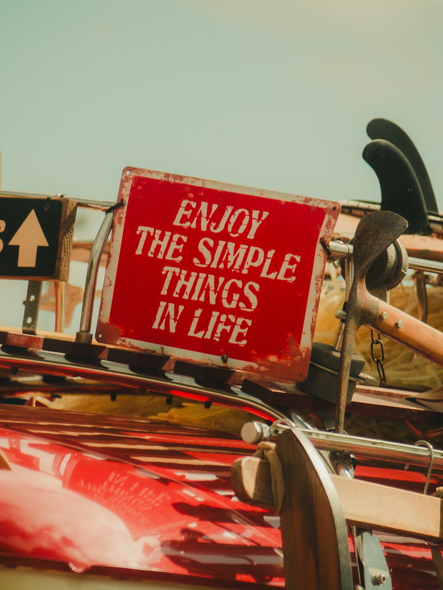 Close-up of a bicycle rack with a red sign that reads 'Enjoy the simple things in life'.