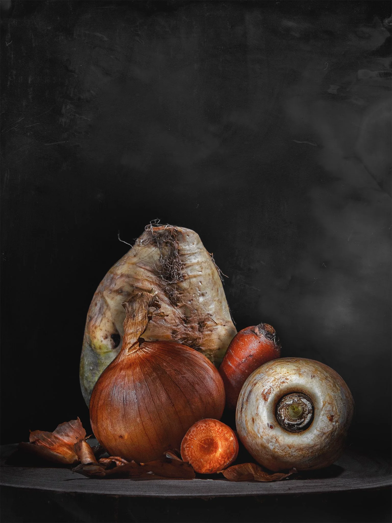 A still life composition of onions, carrots, and mushrooms on a dark surface against a dark background.