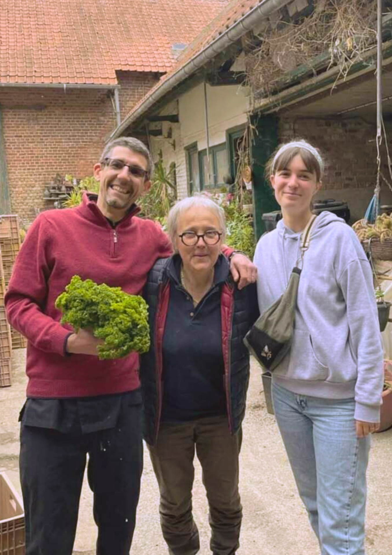 Bertille, Gregory et une productrice locale posant dans la cour d'une ferme.